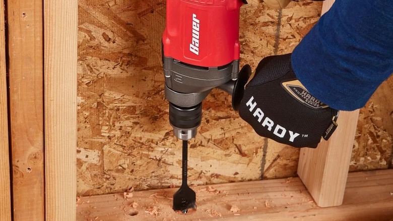 Drilling a hole in timber framing with a Bauer hammer drill.