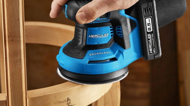 Sanding a chair with a Hercules random orbit sander.