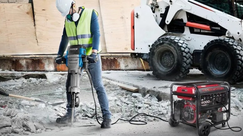 A worker wearing full PPE breaking up concrete with Hercules breaker hammer