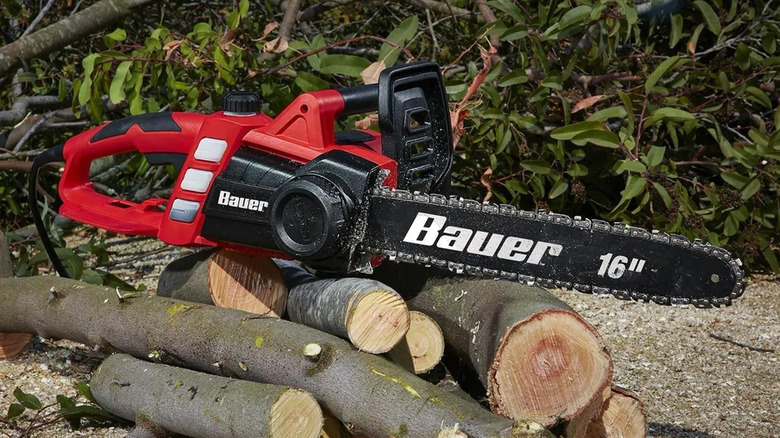 A Bauer chainsaw sitting on top of some wood