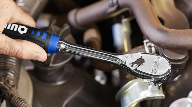 A person using a Quinn socket wrench on a nut