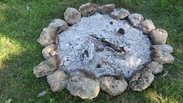 Circular fire pit full of ash enclosed in stones