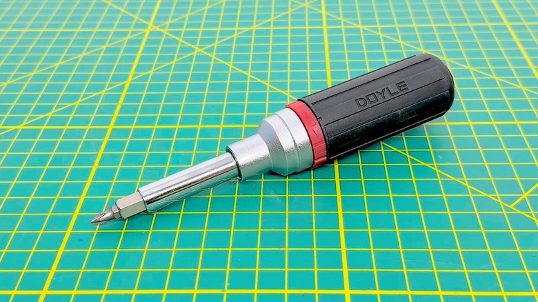 A multibit screwdriver placed on a green surface with yellow patterns.