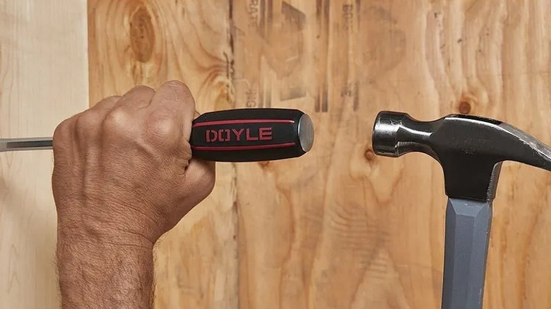 Hitting a screwdriver with a hammer.
