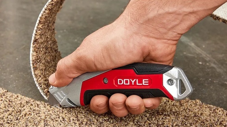 Using a Doyle utility knife to cut through a material.