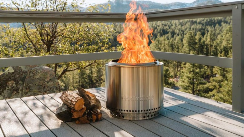 Solo Stove lit next to wood pile on balcony