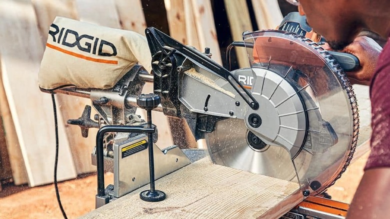 A sliding miter saw being used to cut through a piece of wood.