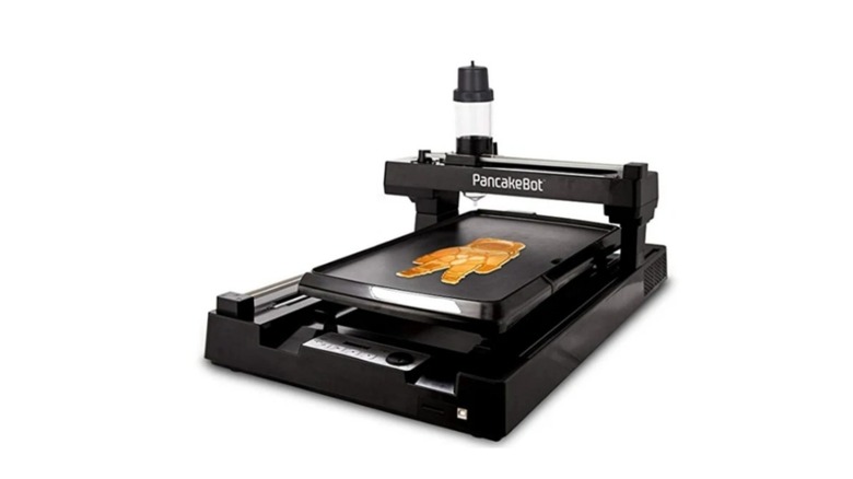A deice that looks like a 3D printer making a spacesuit-shaped pancake