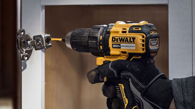 A DeWalt drill being used to install a cabinet door.