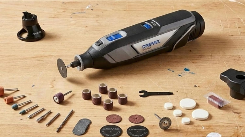 A Dremel 8240 on a wood table with many bits and tools.