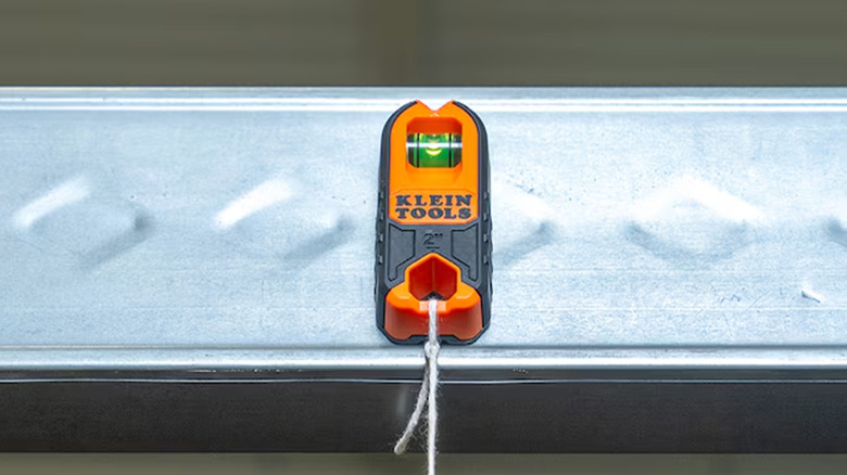 A Klein Tools magnetic stud finder on a piece of metal.