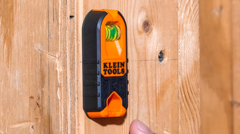A Klein Tools magnetic stud finder affixed to a wood wall.
