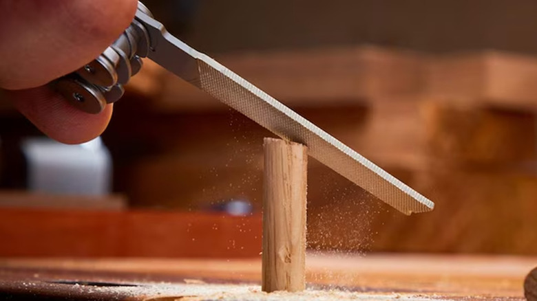 A person using a Leatherman Wave+ to file a piece of wood.
