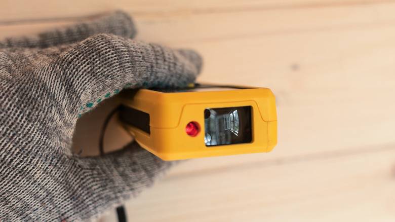 holding a laser distance measurer against a wall