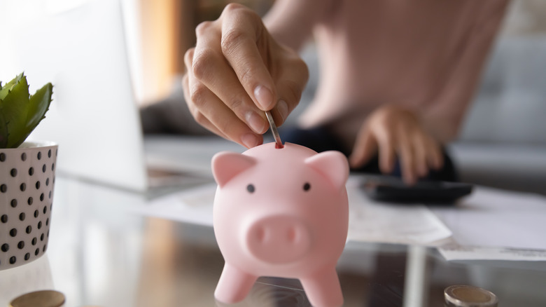 woman putting coin in piggy bank