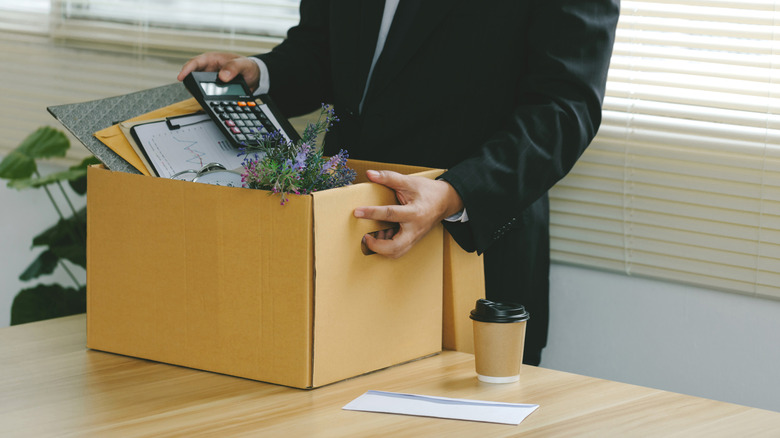 A man putting his things in a box after being fired in an office