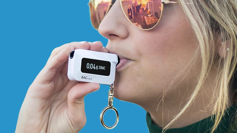 A woman blowing into the BACtrack C6 keychain breathalyzer.
