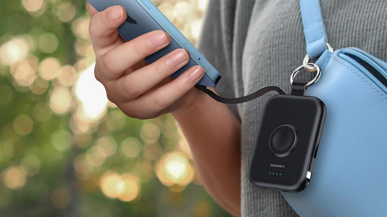 The RORRY CharmGo Portable Charger clipped to a bag charging an iPhone.