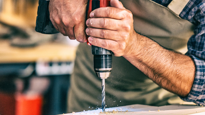 Man drilling into wood in workshop