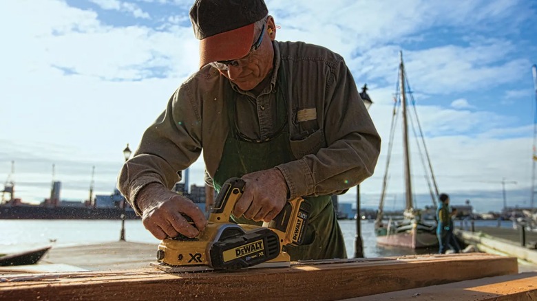 Man planing with DeWalt planer near sea.