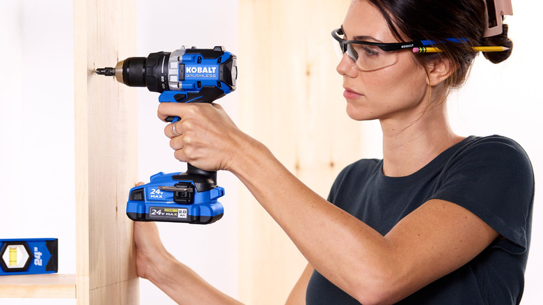 Woman drilling with Kobalt drill on wood.
