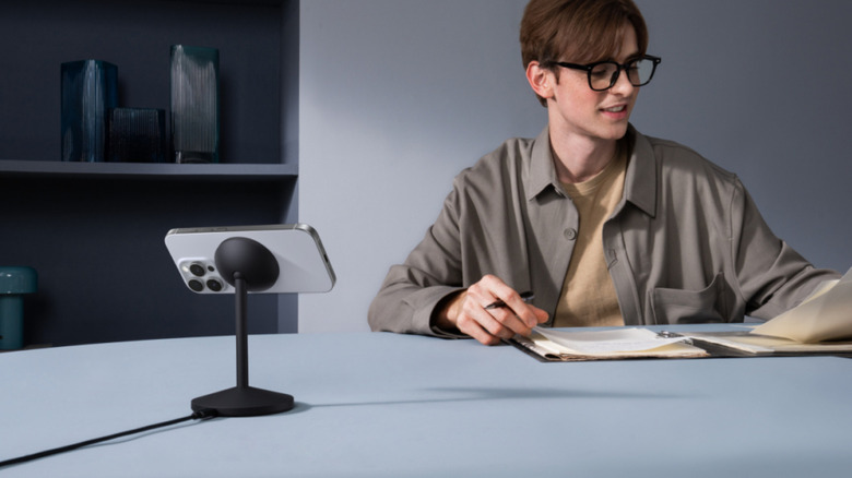 Man reading next to phone on Anker MagSafe Charger Stand.