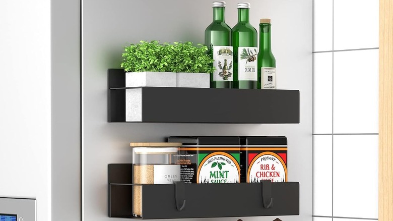 Two magnetic shelves on the side of a fridge holding multiple items.