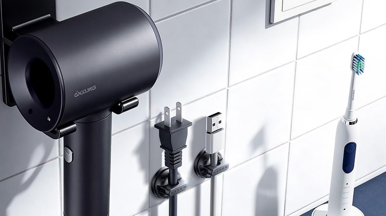 Rotating Cord Holder placed in a bathroom holding a toothbrush USB cable and a hairdryer plug