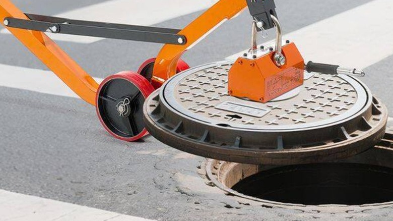 Magnetic lift holding manhole cover