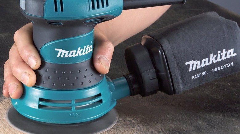 Person using Makita BO5030K Random Orbit Sander