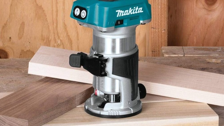Makita XTR01Z router resting atop a small pile of dimensional lumber at a worksite