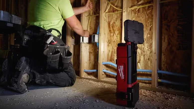 Man working with a floodlight beside him used for illumination.