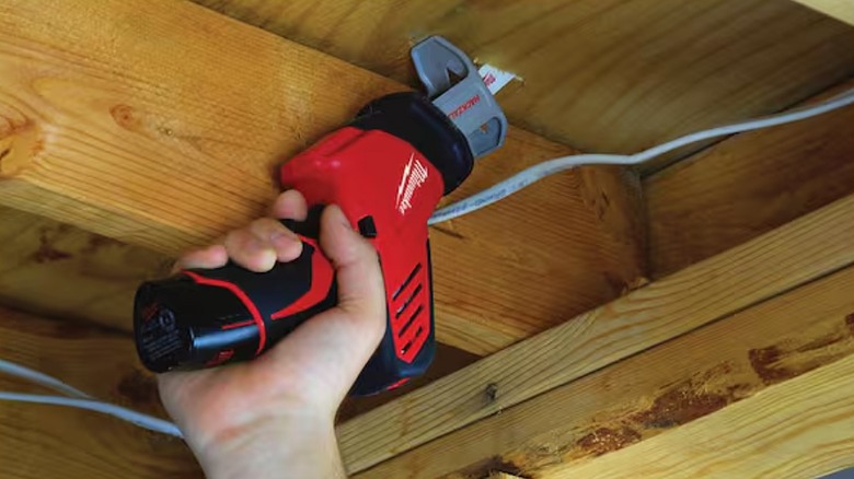 Using reciprocating saw to cut through a wooden surface.