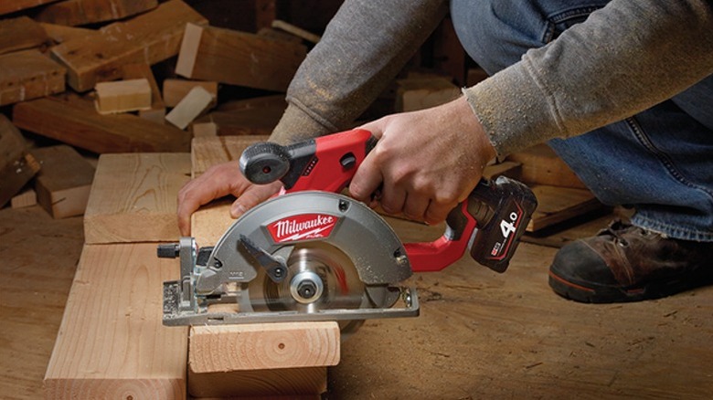 A worker cutting a piece of 2x6 lumber with a circular saw