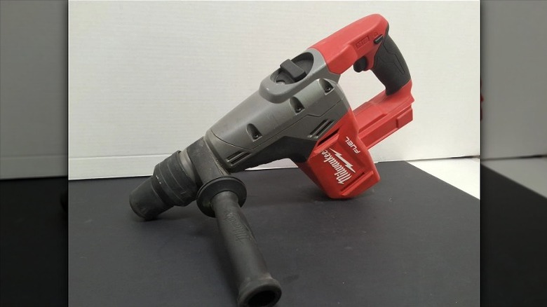 A Milwaukee rotary hammer with a side handle resting on a flat surface