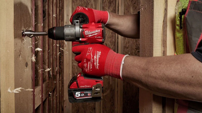 A worker drilling a piece of wood with Milwaukee hammer drill