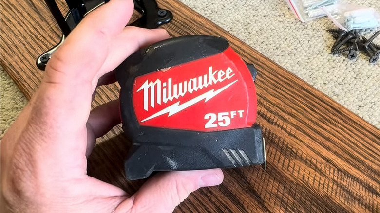 A person holding the Milwaukee Compact 25-Foot SAE Tape Measure.