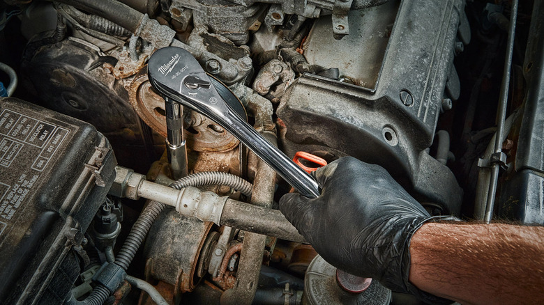 The Milwaukee Drive Ratchet being used on a car engine.
