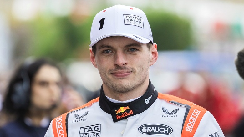 Max looking sharp in his Red Bull gear and a white cap, smiling directly at the camera.