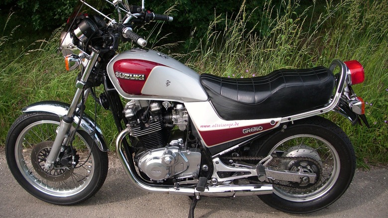 1985 Suzuki 650 Tempter parked in front of weeds and a brick wall