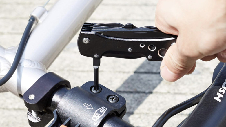 Person using multitool pliers on a bicycle brake bolt