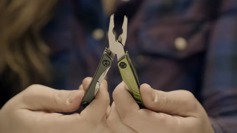 Person holding a multitool with two hands, with the plier tool opened up