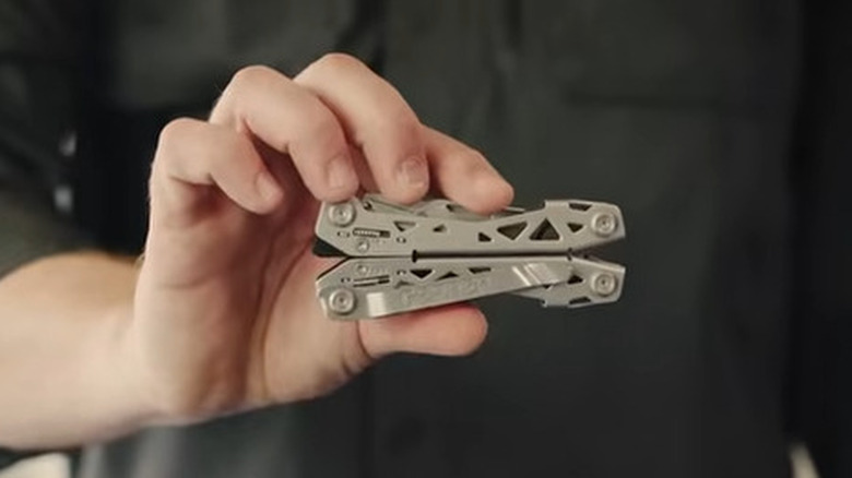 Person holding a closed silver multitool