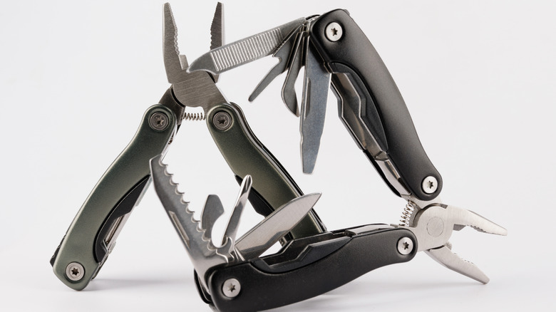 A pair of multitools on a white background with tools extended