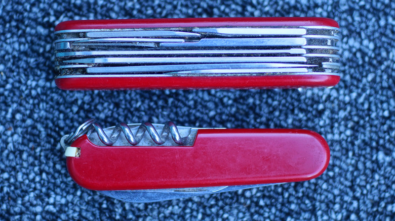 Two red multitools on a blue carpet, one on its side and the other on its back