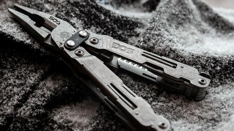A slightly damp silver multitool on a grey blanket
