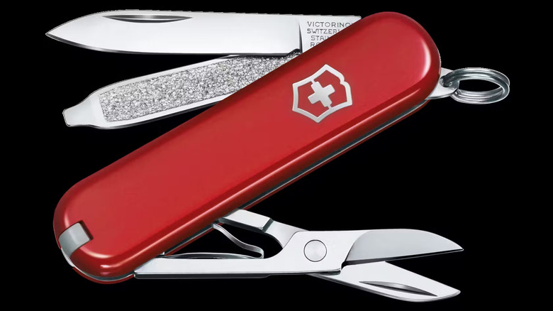 A red Swiss Army knife with silver tools extended