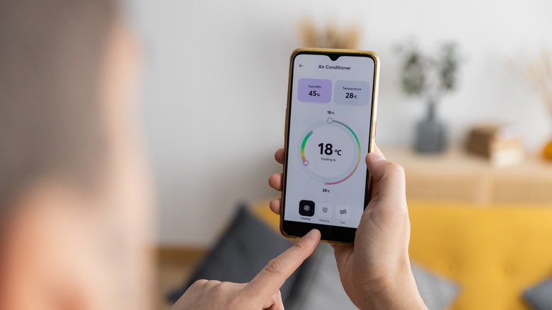 A person adjusting their thermostat on a smartphone