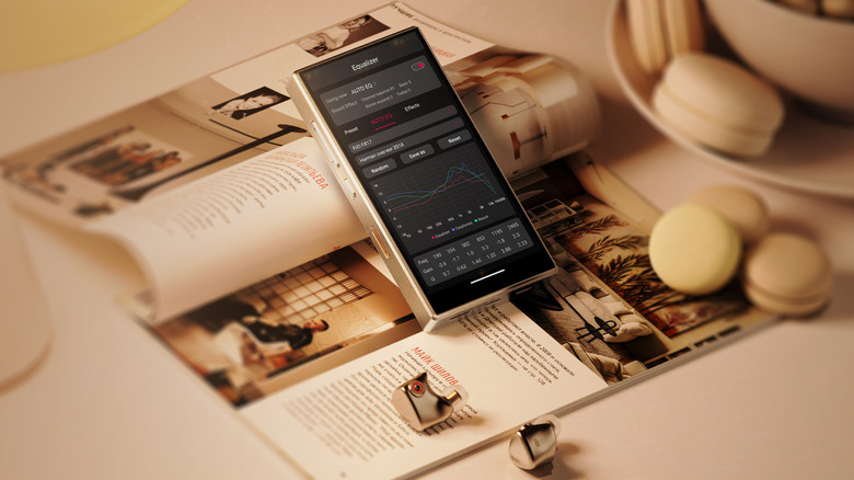 FiiO M33 R2R player resting on an open magazine with some earbuds and decorations