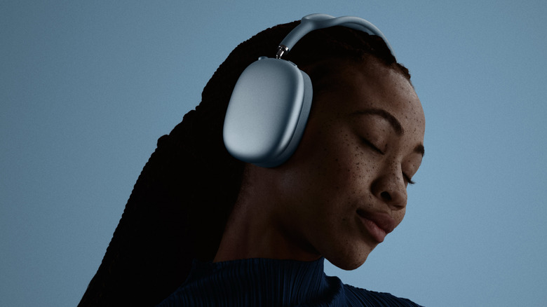 A woman wearing the AirPods Max 2 on a blue background